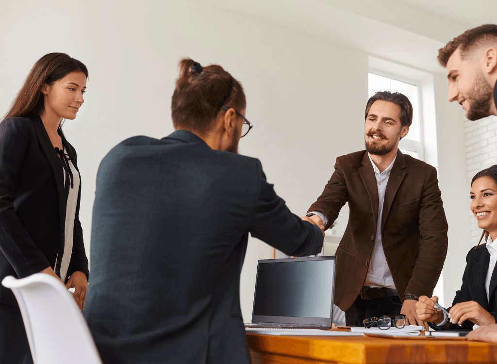 Business team meeting with professionals shaking hands during an IT consultancy or managed IT services discussion.