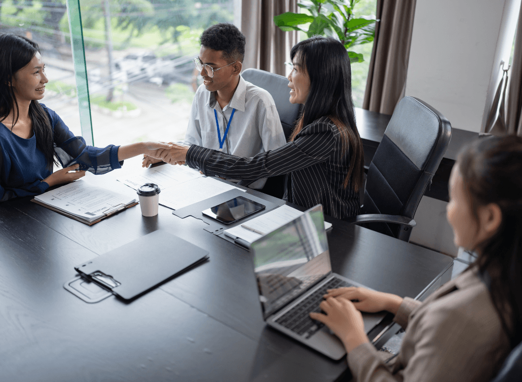 Business team in a meeting discussing managed IT services and shaking hands to confirm partnership and support agreement.